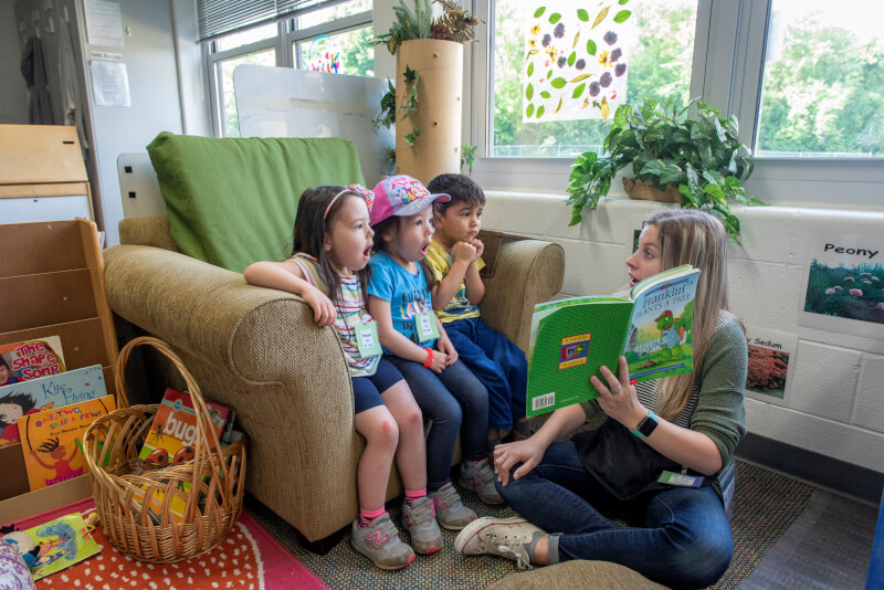 A student teacher reads a story to three children.