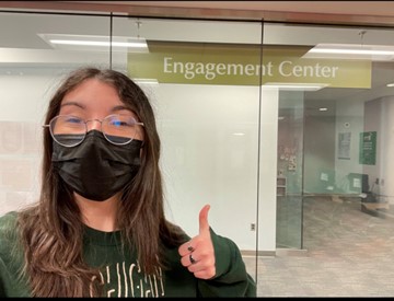 Hackman with mask and a thumbs up in front of the engagement center.