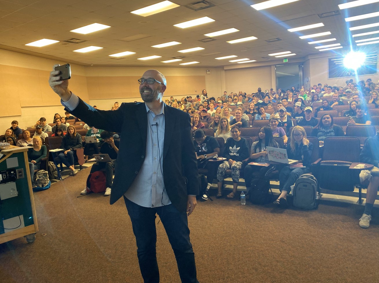 Pradel takes a selfie with a large lecture hall of students.