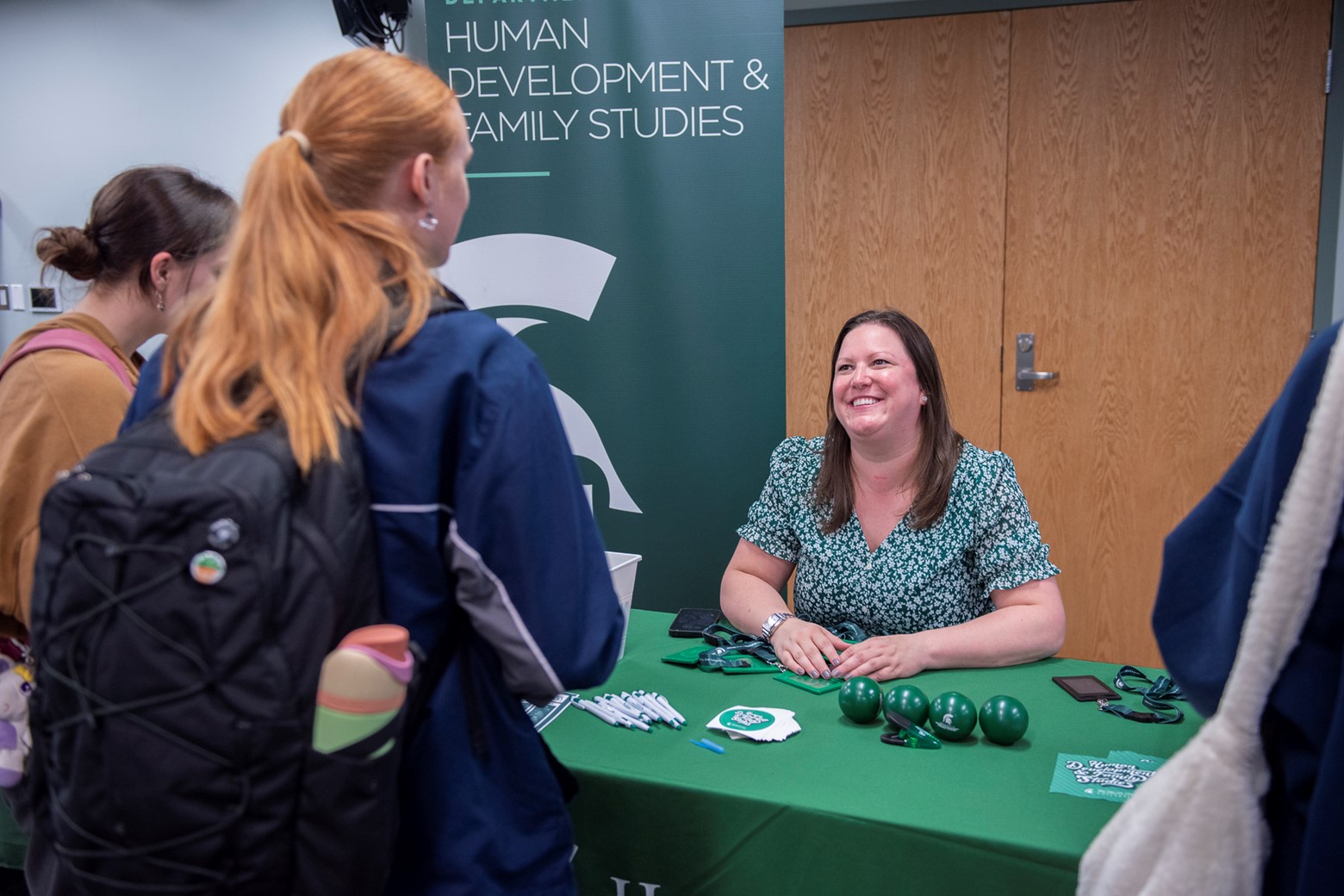 A financial literacy representative talks to students at a booth. 